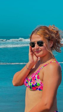 Güneşli bir günde, plajda pembe bikinili ve güneş gözlüklü güzel bir kadın. portre.