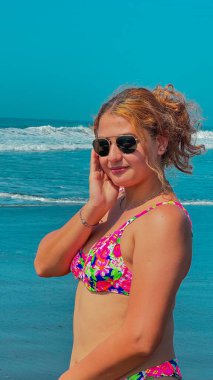 Güneşli bir günde, plajda pembe bikinili ve güneş gözlüklü güzel bir kadın. portre.