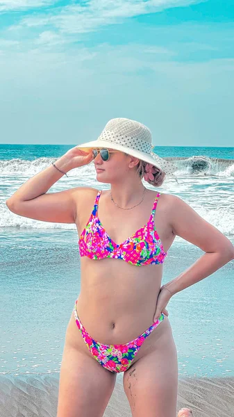 Plajda oturup denize bakan şapkalı güzel bir kadının portresi. yenilenmemiş model, doğal model