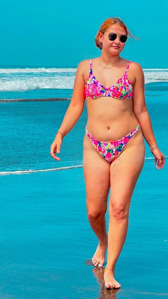 Kumsalda turkuaz suyla bikinili seksi genç kadın.