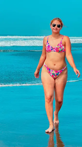 Kumsalda turkuaz suyla bikinili seksi genç kadın.