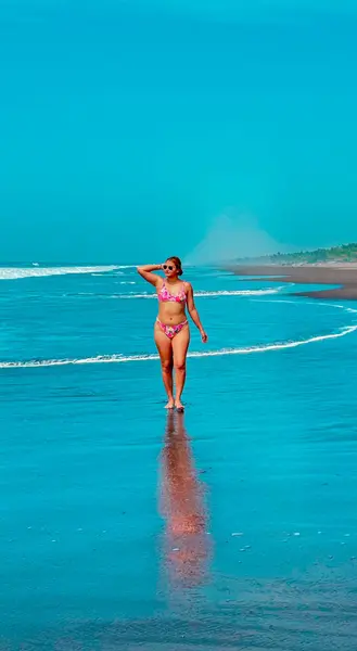 Kumsalda turkuaz suyla bikinili seksi genç kadın.