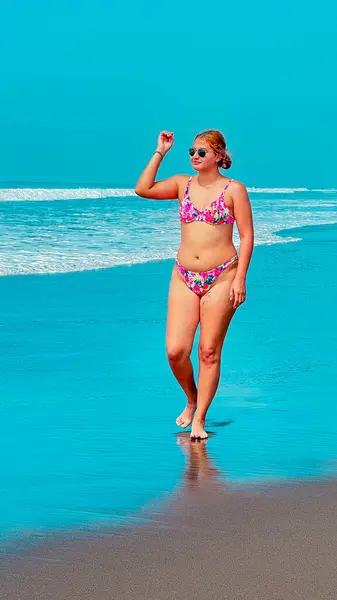 Kumsalda turkuaz suyla bikinili seksi genç kadın.