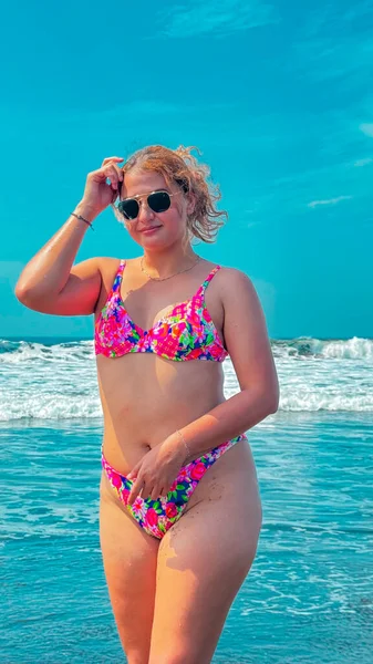 Güneşli bir günde, plajda pembe bikinili ve güneş gözlüklü güzel bir kadın. portre.