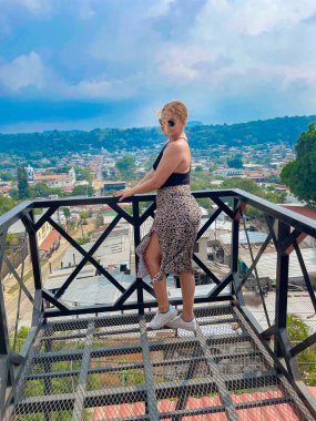Leopar desenli elbiseli güzel bir kadın şehrin gözlem güvertesinde duruyor..