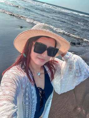 Deniz kıyısında şapkalı ve güneş gözlüklü güzel bir kız. El Salvador sahillerinde