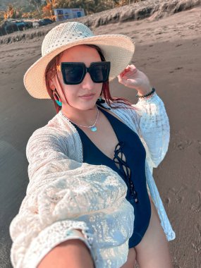 Deniz kıyısında şapkalı ve güneş gözlüklü güzel bir kız. El Salvador sahillerinde