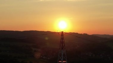 Kırsal alanda, hava manzaralı yüksek voltajlı çelik güç pilonları. Sisli bir sabah, şafak. İHA, güç aktarım hatları üzerinde alçaktan uçuyor. Elektrik kulesi hattı, gündoğumu günbatımı, elektrik hatları ağı