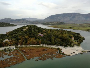 Arnavutluk kıyı şeridi boyunca uzanan mavi deniz ve kumlu plajlar üzerinde yamaç paraşütü manzarası, kıyı manzarası, turizm ve açık hava sporları faaliyetlerini yakalıyor
