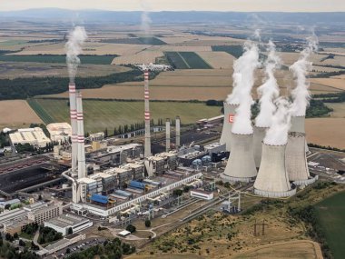 Pocerady, Czech republic - June 28 2023: Aerial panorama view of Pocerady coal power plant with smokestacks and cooling towers in the middle of nothern Bohemian landscape.Huge energy sources