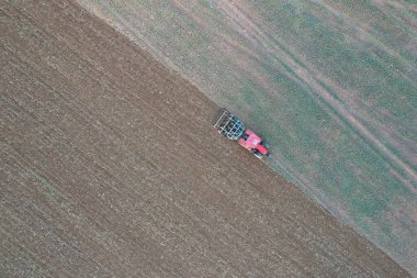 Tarım tarlasında ekin eken traktörlü bir çiftçi. Bitkiler, buğday. Tarımsal ekinlerle dolu bir tarlada toprak gevşemesi, havadan çekim. Traktör toprağı işliyor. İnsansız hava aracı görüntüsü. Tarım. 