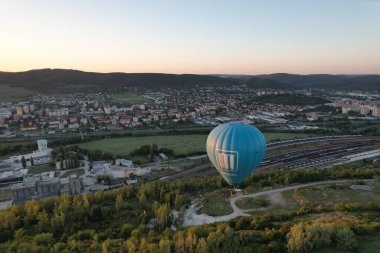 Sıcak hava balonu Beroun şehir kırsalında alçaktan uçuyor, manzaranın havadan manzarasını sunuyor..
