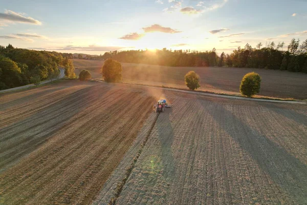 Farmer with tractor seeding-sowing crops at agricultural field. Plants, wheat.Soil loosening in a field with agricultural crops, aerial shot. The tractor processes the soil.drone view.Agricultural
