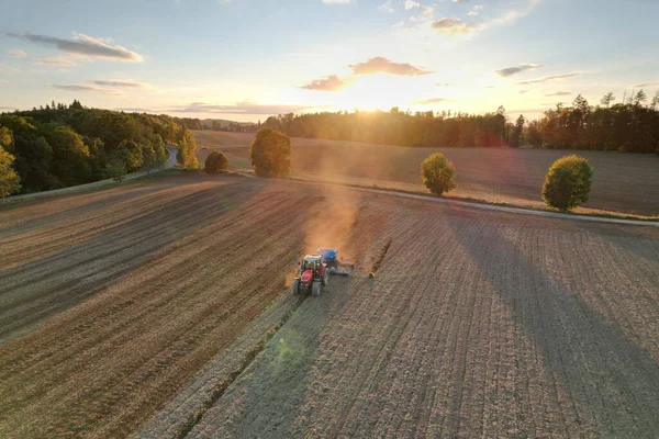 Farmer with tractor seeding-sowing crops at agricultural field. Plants, wheat.Soil loosening in a field with agricultural crops, aerial shot. The tractor processes the soil.drone view.Agricultural