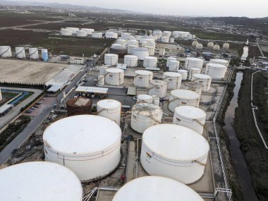 Petrol ürünleri ve gaz için depolama tanklarının yer aldığı bir petrol rafinerisinin hava manzarası, sanayi altyapısını gösteriyor.
