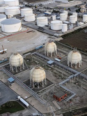 Petrol ürünleri ve gaz için depolama tanklarının yer aldığı bir petrol rafinerisinin hava manzarası, sanayi altyapısını gösteriyor.
