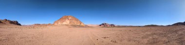 Ürdün 'deki Wadi Rum çölünün panoramik manzarası. Dağlar ve kayaların oluşturduğu düz kum üzerinde hareket eden bulutlar. Yeryüzünün güzelliğini keşfedin. Ulusal park manzarası. UNESCO