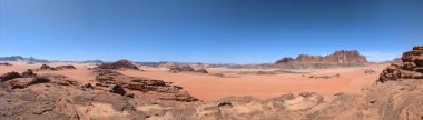 Ürdün 'deki Wadi Rum çölünün panoramik manzarası. Dağlar ve kayaların oluşturduğu düz kum üzerinde hareket eden bulutlar. Yeryüzünün güzelliğini keşfedin. Ulusal park manzarası. UNESCO