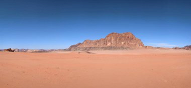 Ürdün 'deki Wadi Rum çölünün panoramik manzarası. Dağlar ve kayaların oluşturduğu düz kum üzerinde hareket eden bulutlar. Yeryüzünün güzelliğini keşfedin. Ulusal park manzarası. UNESCO