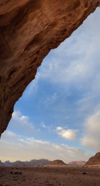 Ürdün 'deki Wadi Rum çölünün panoramik manzarası. Dağlar ve kayaların oluşturduğu düz kum üzerinde hareket eden bulutlar. Yeryüzünün güzelliğini keşfedin. Ulusal park manzarası. UNESCO