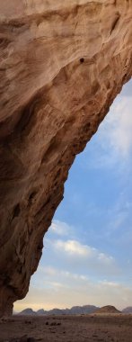 Ürdün 'deki Wadi Rum çölünün panoramik manzarası. Dağlar ve kayaların oluşturduğu düz kum üzerinde hareket eden bulutlar. Yeryüzünün güzelliğini keşfedin. Ulusal park manzarası. UNESCO
