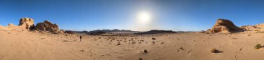 Ürdün 'deki Wadi Rum çölünün panoramik manzarası. Dağlar ve kayaların oluşturduğu düz kum üzerinde hareket eden bulutlar. Yeryüzünün güzelliğini keşfedin. Ulusal park manzarası. UNESCO