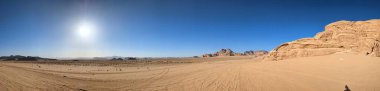 Ürdün 'deki Wadi Rum çölünün panoramik manzarası. Dağlar ve kayaların oluşturduğu düz kum üzerinde hareket eden bulutlar. Yeryüzünün güzelliğini keşfedin. Ulusal park manzarası. UNESCO