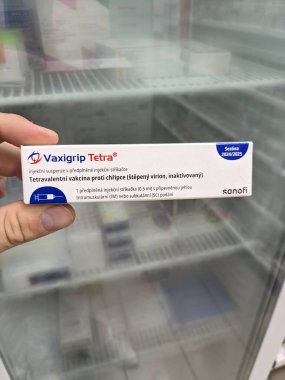 Prag, Çek Cumhuriyeti - 14 Ekim 2023: Eczane kavramı-Vaxigrip tetra aşı paketi bir buzdolabı eczacısının elinin önünde. Bu aşı sizi veya çocuğunuzu gribe karşı korumaya yardımcı olur (grip).)