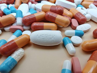 Eczacılık görsel kapsüllerindeki renkli kapsüllerin ve tabletlerin üzerine MerCK damgalı beyaz hap.