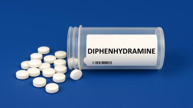 Diphenhydramine plastik ilaç kutusu ve masada tabletler.