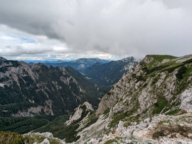 Sloven Alplerinin tepelerinin bulutlarla kaplı olduğu Logarska Dolina Vadisi 'nin panoramik manzarası.
