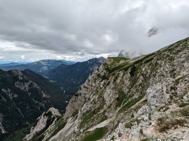 Sloven Alplerinin tepelerinin bulutlarla kaplı olduğu Logarska Dolina Vadisi 'nin panoramik manzarası.