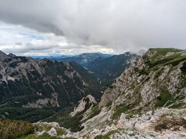 Sloven Alplerinin tepelerinin bulutlarla kaplı olduğu Logarska Dolina Vadisi 'nin panoramik manzarası.
