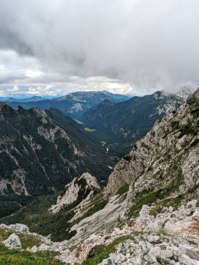 Sloven Alplerinin tepelerinin bulutlarla kaplı olduğu Logarska Dolina Vadisi 'nin panoramik manzarası.