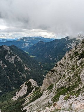 Sloven Alplerinin tepelerinin bulutlarla kaplı olduğu Logarska Dolina Vadisi 'nin panoramik manzarası.