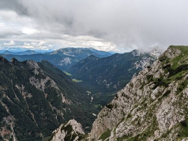 Sloven Alplerinin tepelerinin bulutlarla kaplı olduğu Logarska Dolina Vadisi 'nin panoramik manzarası.