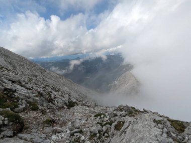 Sloven Alplerinin tepelerinin bulutlarla kaplı olduğu Logarska Dolina Vadisi 'nin panoramik manzarası.