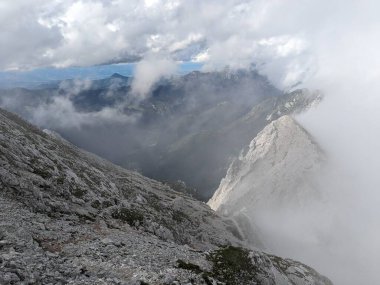 Sloven Alplerinin tepelerinin bulutlarla kaplı olduğu Logarska Dolina Vadisi 'nin panoramik manzarası.