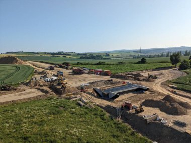 Ağır kazıcılar ve çöp kamyonları büyük bir bölge kenti yakınlarında yeni bir çevre yolu inşaatında çalışıyor.