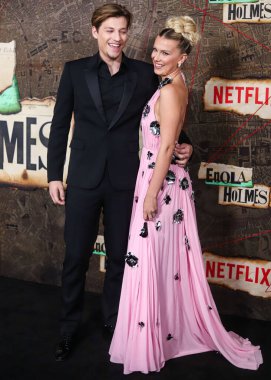 American actor Jake Bongiovi and girlfriend/British actress Millie Bobby Brown wearing Louis Vuitton arrive at the World Premiere Of Netflix's 'Enola Holmes 2' held at The Paris Theater on October 27, 2022 in Manhattan, New York City, New York, USA clipart
