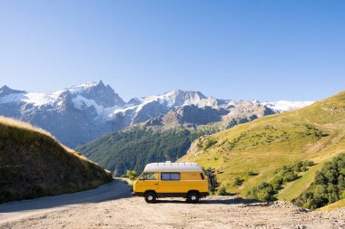 Arka planda yüksek dağlar olan ormana park etmiş Retro karavan, Ecrins Ulusal Parkı, Fransa
