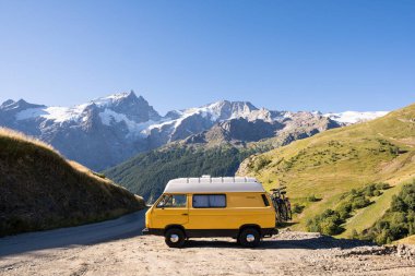 Arka planda yüksek dağlar olan ormana park etmiş Retro karavan, Ecrins Ulusal Parkı, Fransa