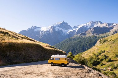 Arka planda yüksek dağlar olan ormana park etmiş Retro karavan, Ecrins Ulusal Parkı, Fransa
