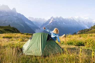 Mont Blanc tepesine tepeden bakan Alps dağlarındaki çadırda uyanan genç bir kadın. Chamonix, Fransa 'da sürdürülebilir turizm
