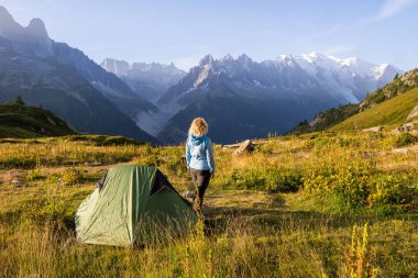 Mont Blanc tepesine bakan Alps dağlarında çadırda dinlenen genç bir kadın. Chamonix, Fransa 'da sürdürülebilir turizm.