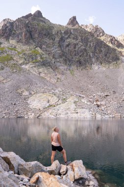 Fransız Alp Dağları 'nda Mont Blanc zirvesine bakan gölde yürüyüş yapan bir kadın. Avrupa 'da sürdürülebilir turizm. Dikey yönelim.