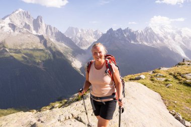 Genç ve gülümseyen bir kadın Fransız Alpleri 'nde Mont Blanc zirvesine bakan sırıklarla yürüyüş yapıyor. Avrupa 'da sürdürülebilir turizm