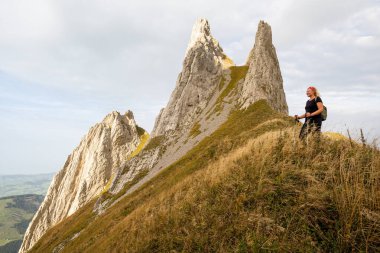 Young woman hiking in Appenzell Innerrhoden canton of Swiss Alps, Switzerland. Rocky mountain peaks on the background. clipart