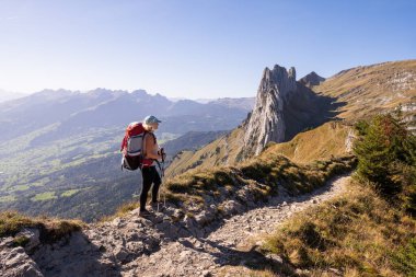 Young woman with backpack hiking in Appenzell Innerrhoden canton of Swiss Alps, Switzerland. Rocky mountain peaks on the background. clipart