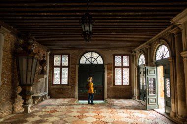 Venedik mimarisini keşfeden genç bir kadın, İtalya 'da kanal erişimi olan geleneksel bir binanın içinde duruyor..